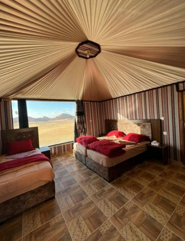 a bedroom with two beds and a large window at Rum ahmad in Wadi Rum