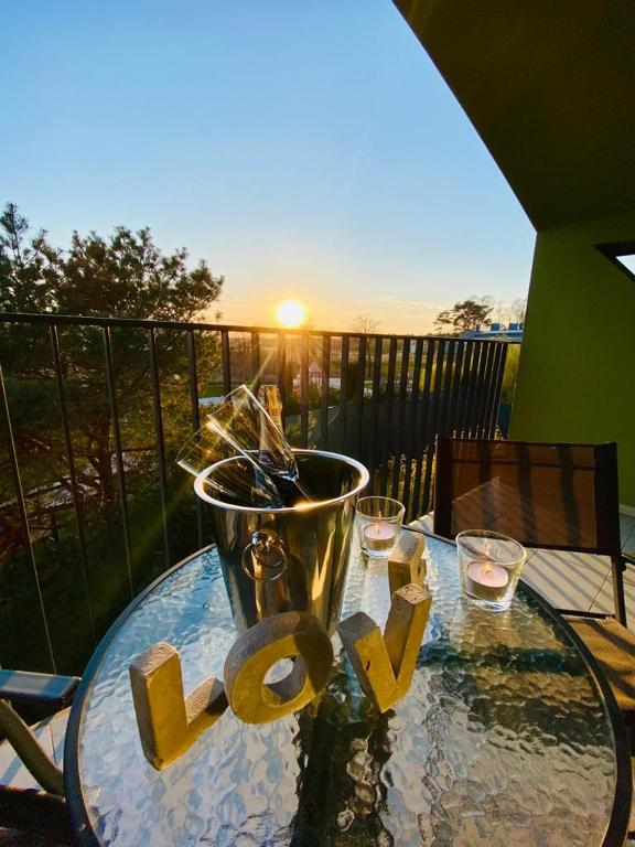 a glass table with a bucket and glasses on a balcony at Apartamenty Pod Żaglami in Dziwnówek