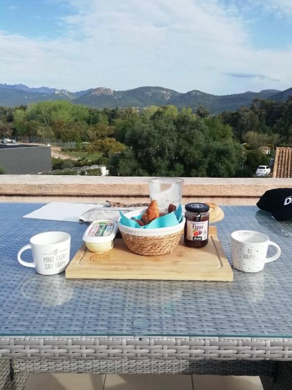 une table de pique-nique avec un panier de nourriture et des tasses dans l'établissement Altura, à Zonza