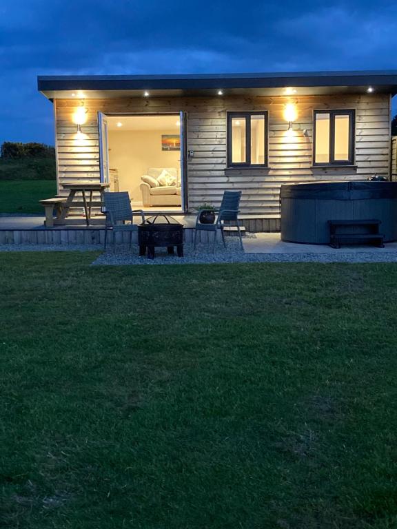 a small house with a patio at night at MAESLLAN CABINS 'Hud Y Machlud' in Cross Inn