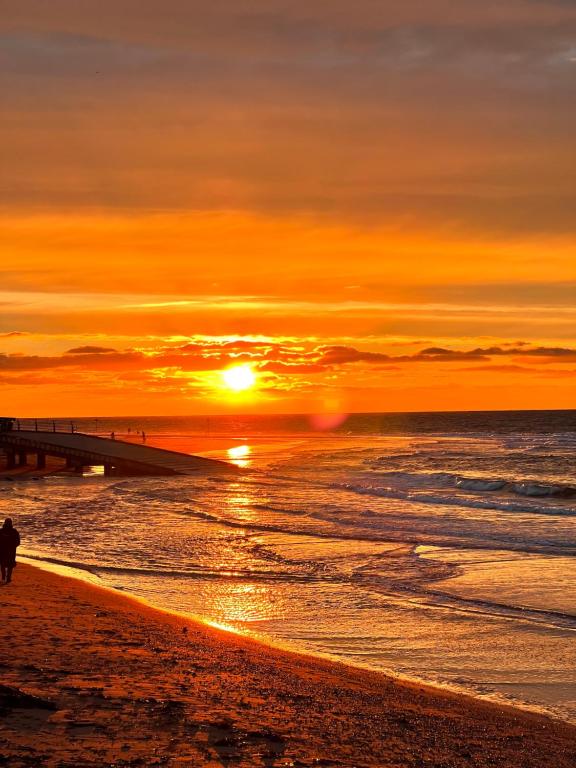 puesta de sol en una playa con muelle en Sandy feet retreat, en Exmouth