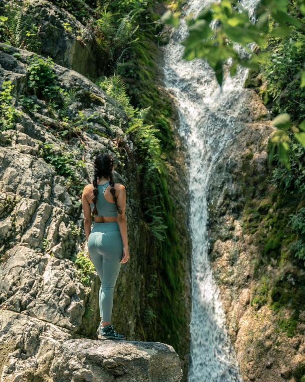 a woman standing on a rock in front of a waterfall at Cabañas Cascada del Barro in Guajuquito
