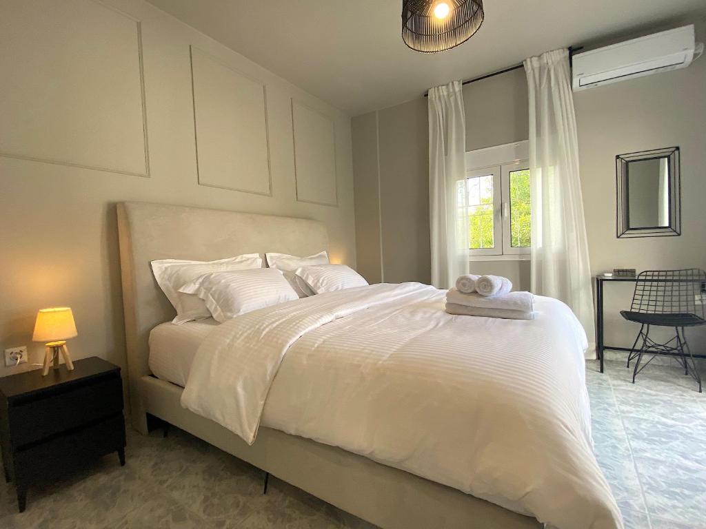 Schlafzimmer mit einem Bett mit weißer Bettwäsche und einem Fenster in der Unterkunft Sand by Aestas Suites in Artemida