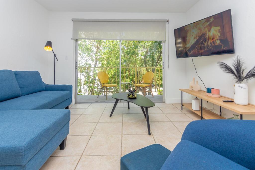 een woonkamer met een blauwe bank en een tafel bij One Bedroom Apartment - with Parking & Balcony - Heart of Wynwood in Miami