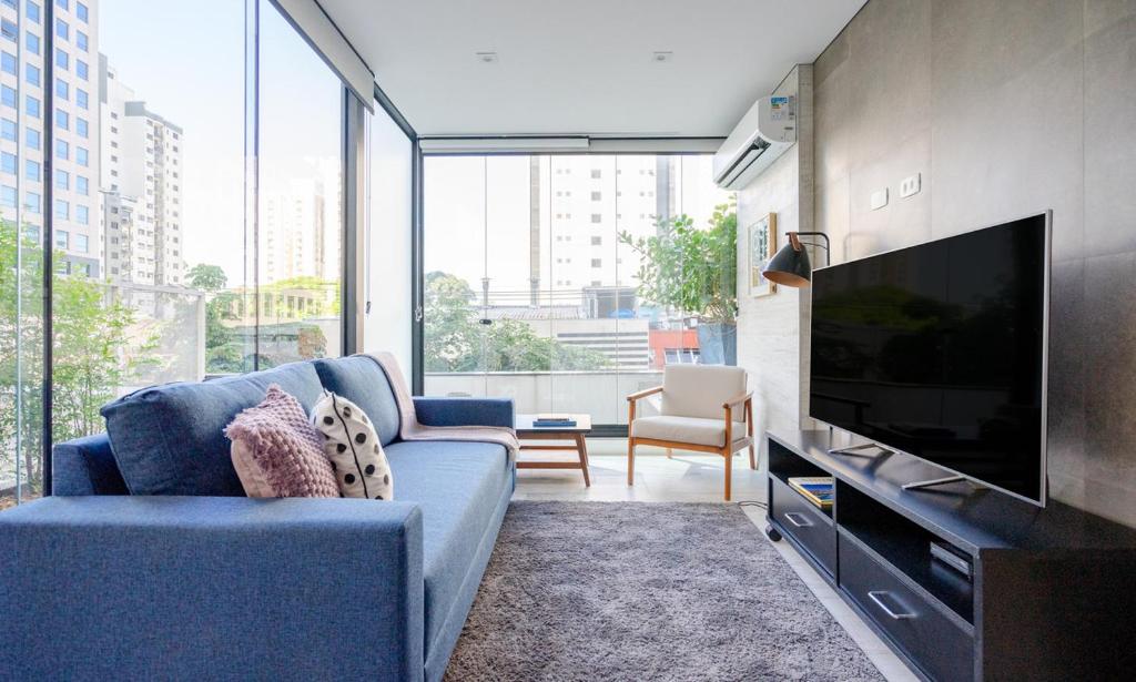 uma sala de estar com um sofá azul e uma televisão em Tabas - VN Gomes de Carvalho em São Paulo