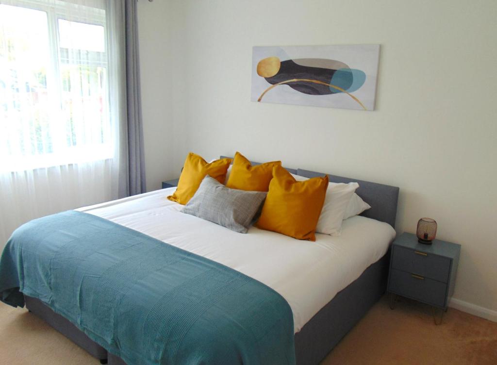 - une chambre avec un lit doté d'oreillers jaunes et bleus dans l'établissement Cosy Two Bedroom Bungalow in Hutton Brentwood with Free Parking & Garden, à Hutton