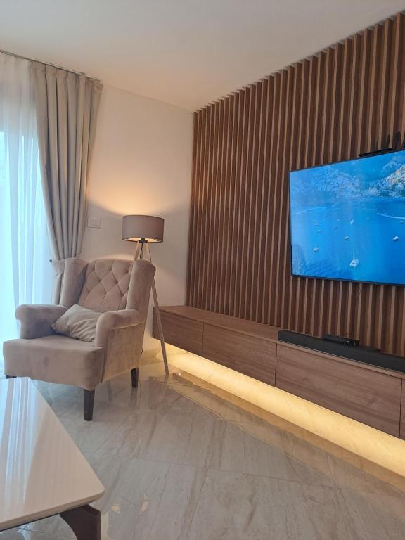 ein Wohnzimmer mit einem Stuhl und einem TV an der Wand in der Unterkunft Lux Apartment Jovanovic in Tivat