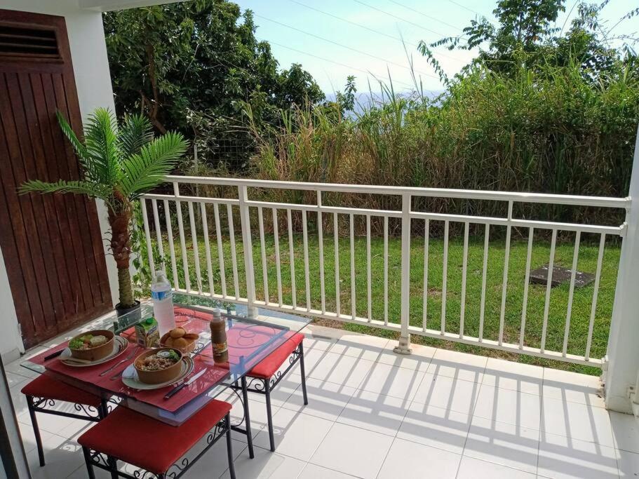 patio con mesa y sillas en el balcón en Studio vue mer, calme avec terrasse à Schoelcher, en Schœlcher