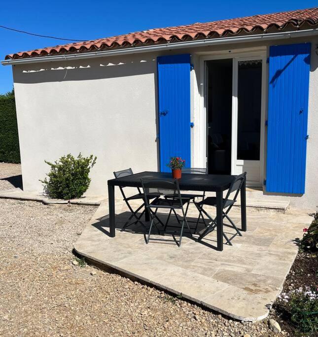 une table noire devant une maison avec portes bleues dans l'établissement Valensole, à Valensole