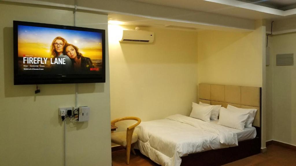 Zimmer mit einem Bett und einem TV an der Wand in der Unterkunft Stylish Studio apartment with Pool and Gym in Daressalam