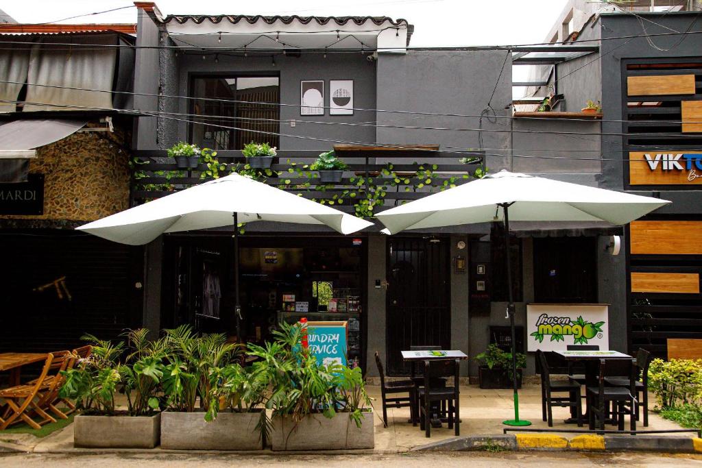 two tables and chairs with umbrellas in front of a building at Casa Jiwa In Provenza in Medellín