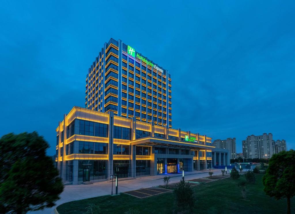 um edifício alto com um sinal verde em cima em Holiday Inn Express Lanzhou New Area, an IHG Hotel em Lanzhou