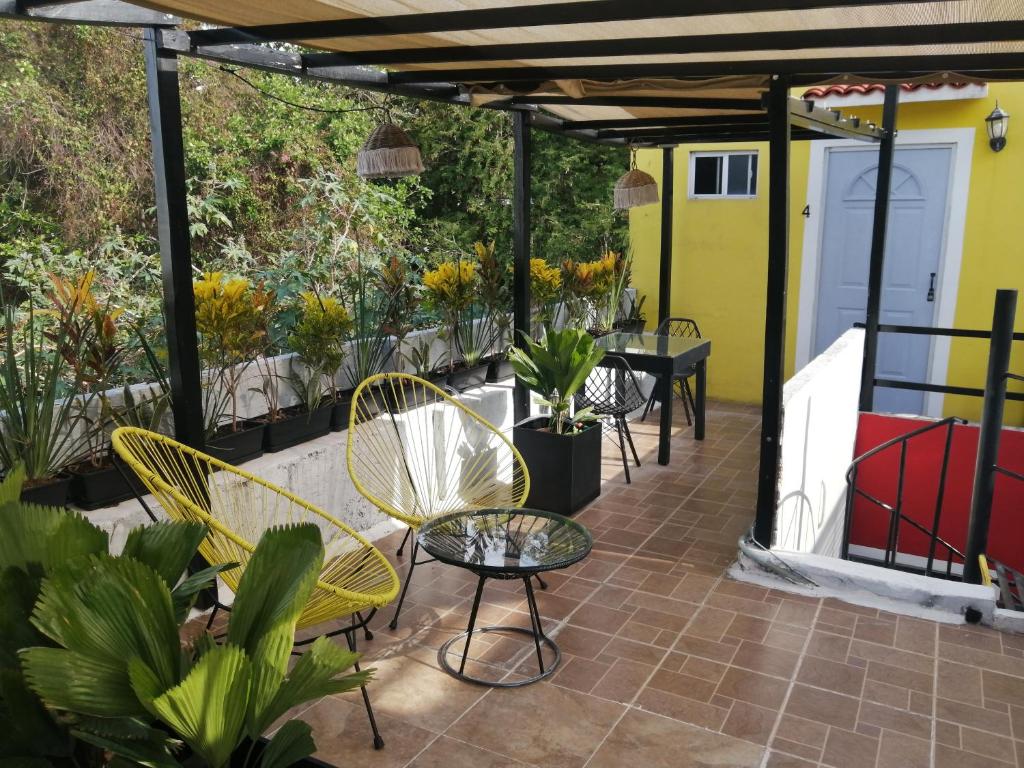 um pátio com cadeiras, mesas e plantas em Guest house La Casa del Quetzal em Mérida