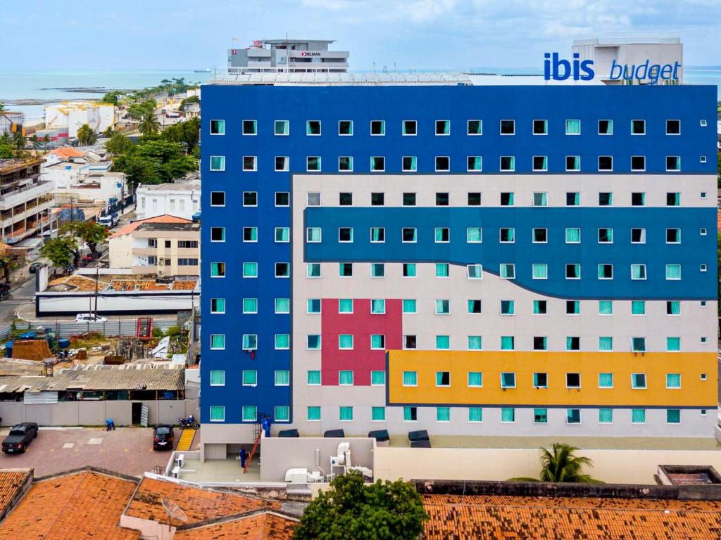 a large blue building with colorful windows in a city at ibis budget Maceió Pajuçara in Maceió