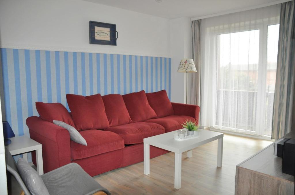 - un salon avec un canapé rouge et une table dans l'établissement Ort Lemkenhafen Segler, à Fehmarn
