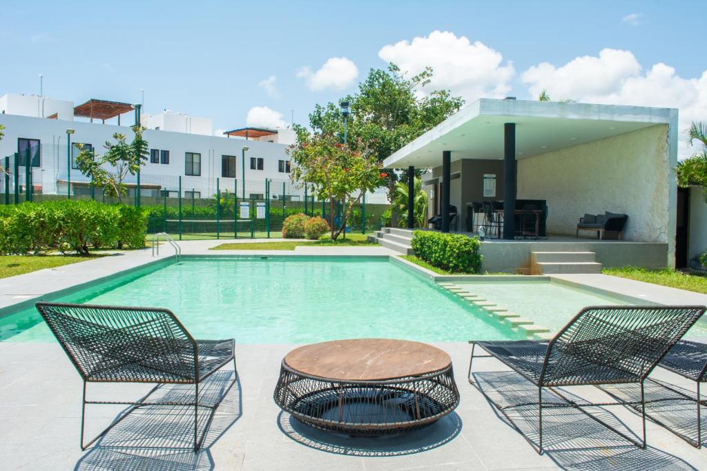 una piscina con due sedie e un tavolo di Paraíso Playa Bonita- Roof Top a Playa del Carmen