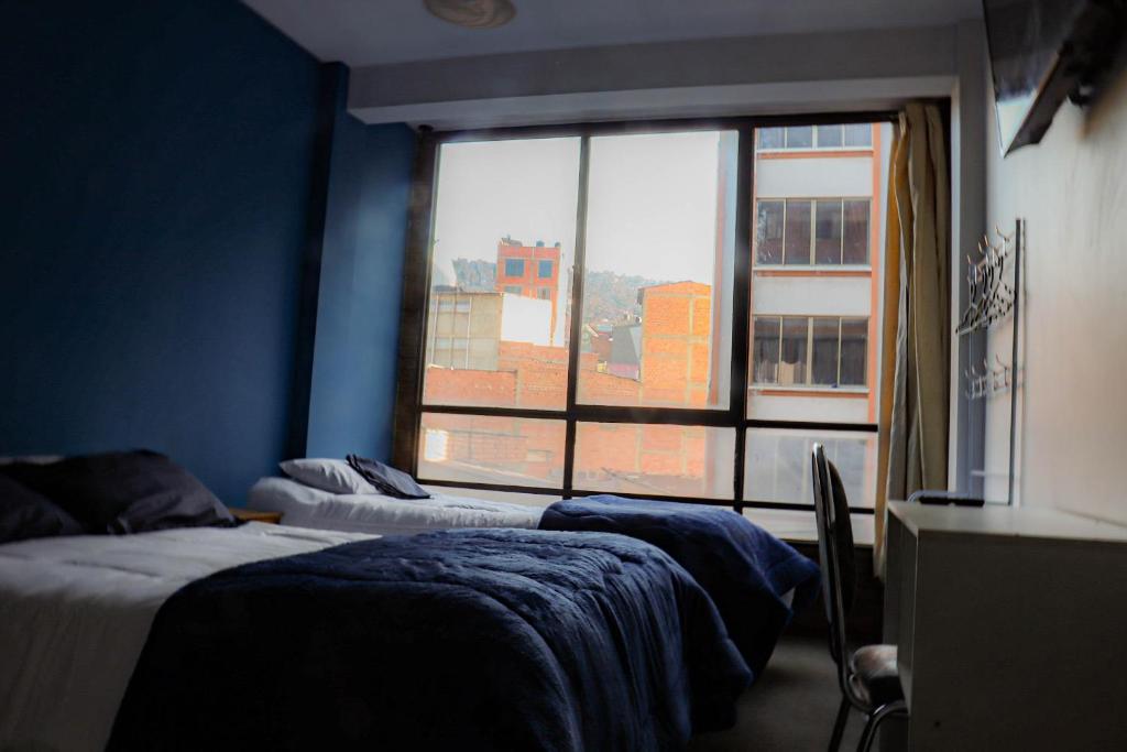 ラパスにあるLobo Hostel La Pazのベッドが2つと大きな窓がある寝室