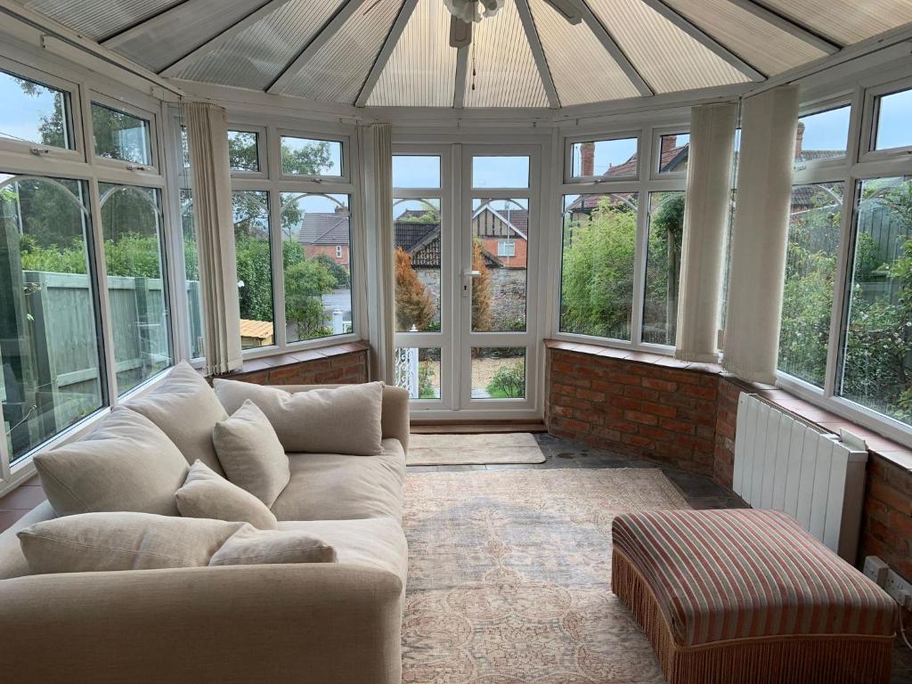 a living room with a couch in a conservatory with windows at Rose Cottage Glastonbury in Glastonbury