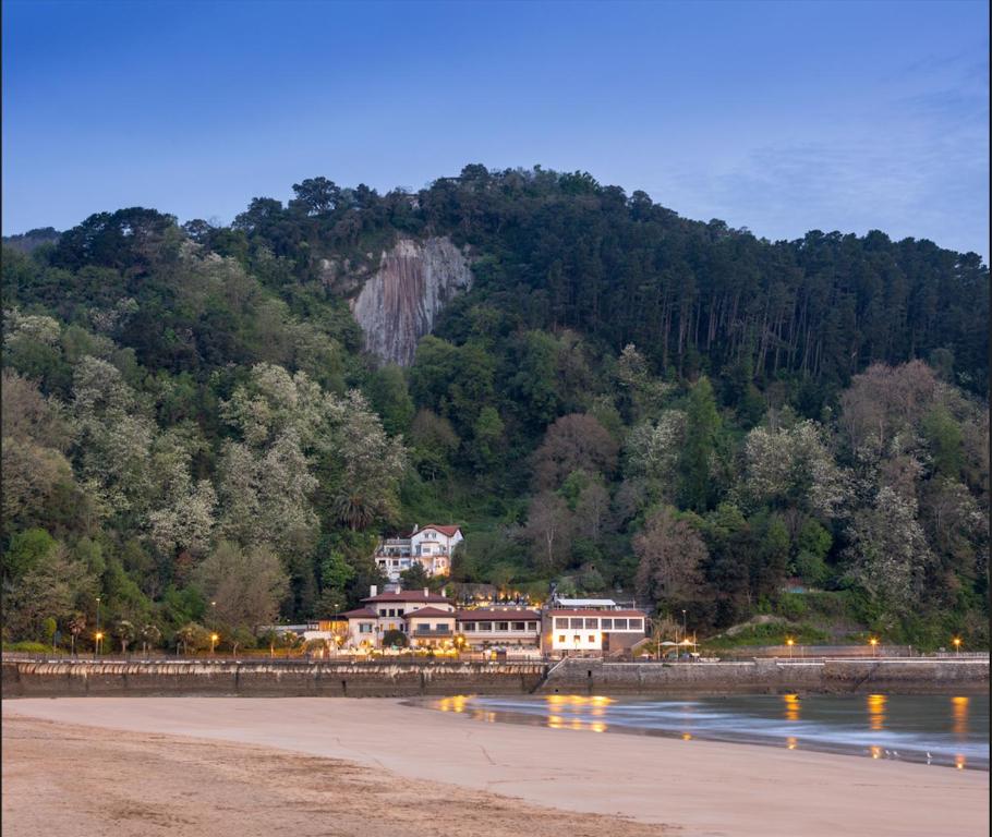 a house on the beach next to a mountain at Hotel Ur Bare in Zarautz