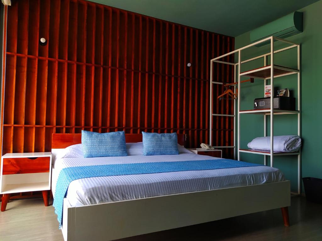 a bedroom with a bed with a red wall at Hotel Momotus in Tuxtla Gutiérrez