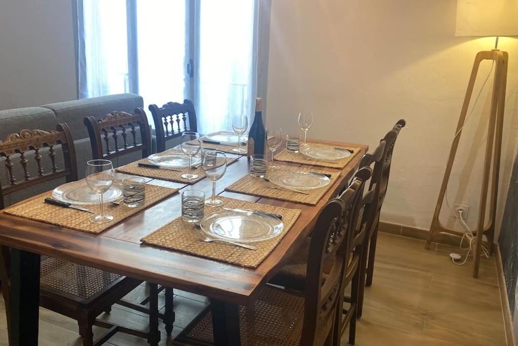 a wooden table with plates and glasses on it at * Logement Haut de gamme Centre * in Perpignan