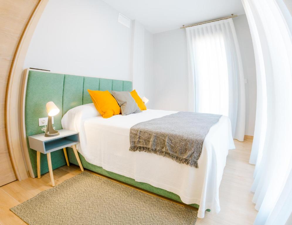 1 dormitorio con cama blanca y cabecero verde en Apartamentos Villa Zoila Nigrán, en Nigrán