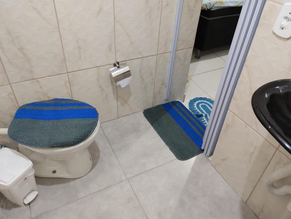 a bathroom with a toilet with a blue and green rug at Hospedagem Roze - in São José de Pedra Menina