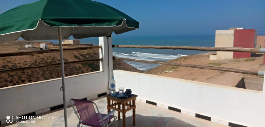 d'une terrasse avec une table et un parasol vert. dans l'établissement Repos Surf House 1, à Sidi Ifni
