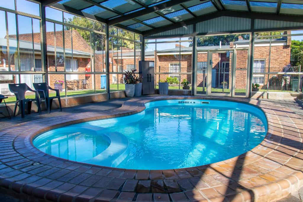 a swimming pool in a pavilion with blue water at Arkana Motor Inn & Terrace Apartments in Mount Gambier