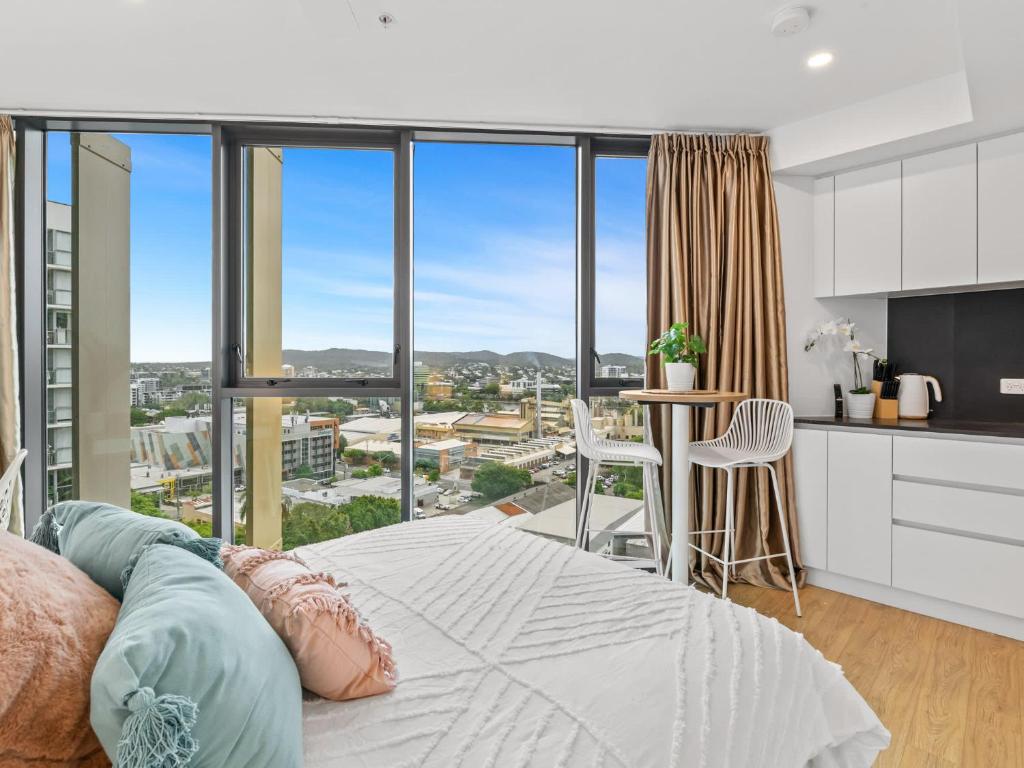 a bedroom with a bed and a view of a city at Brand-New Central Studio Apart with Views in Brisbane