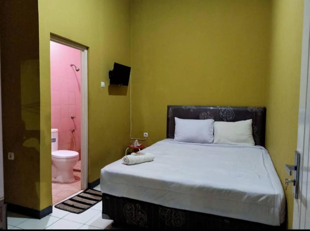 a bedroom with a bed and a bathroom with a toilet at PONDOK CHILLY in Cirebon