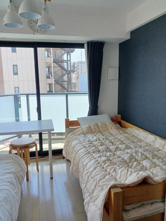 1 dormitorio con cama, mesa y ventana grande en オリエントシティ南堀江Ⅱ en Osaka