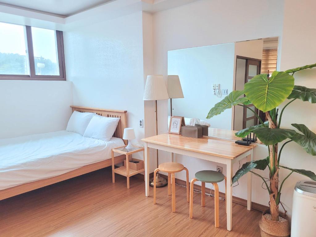 Schlafzimmer mit einem Bett, einem Schreibtisch und einem Tisch in der Unterkunft Seogwiporto in Seogwipo