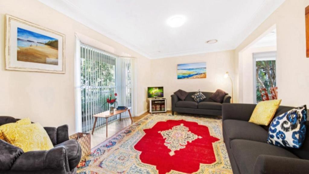 una sala de estar con 2 sofás y una alfombra roja en Family Comfort - Pearl Beach Pet Friendly, en Pearl Beach