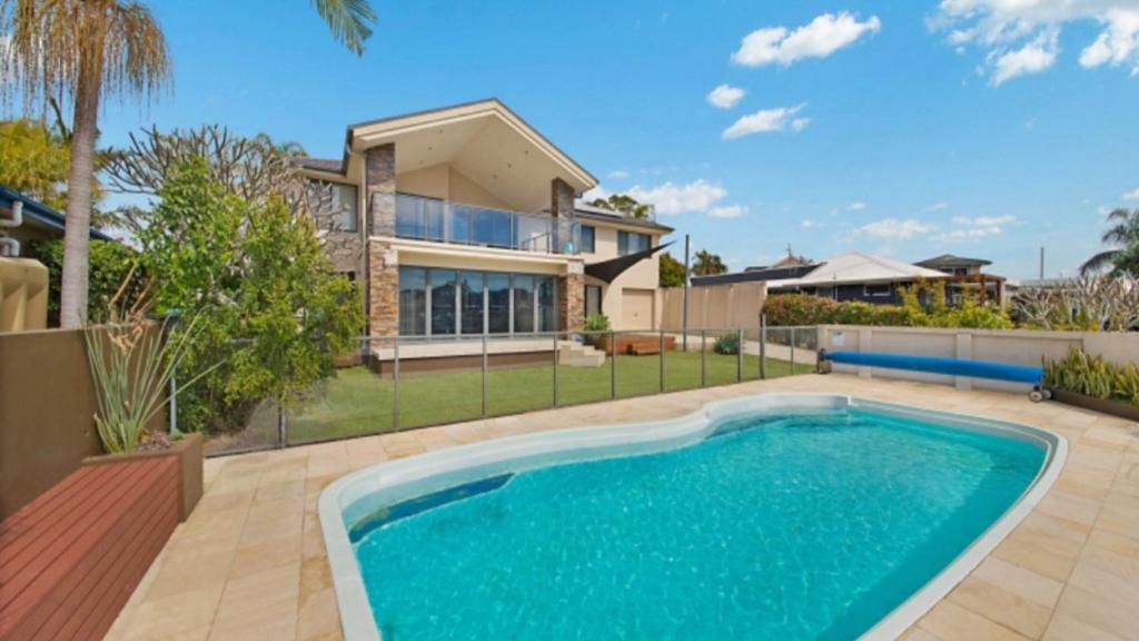 a house with a swimming pool in front of a house at Tranquil Lagoon - Waterfront Luxury in Daleys Point