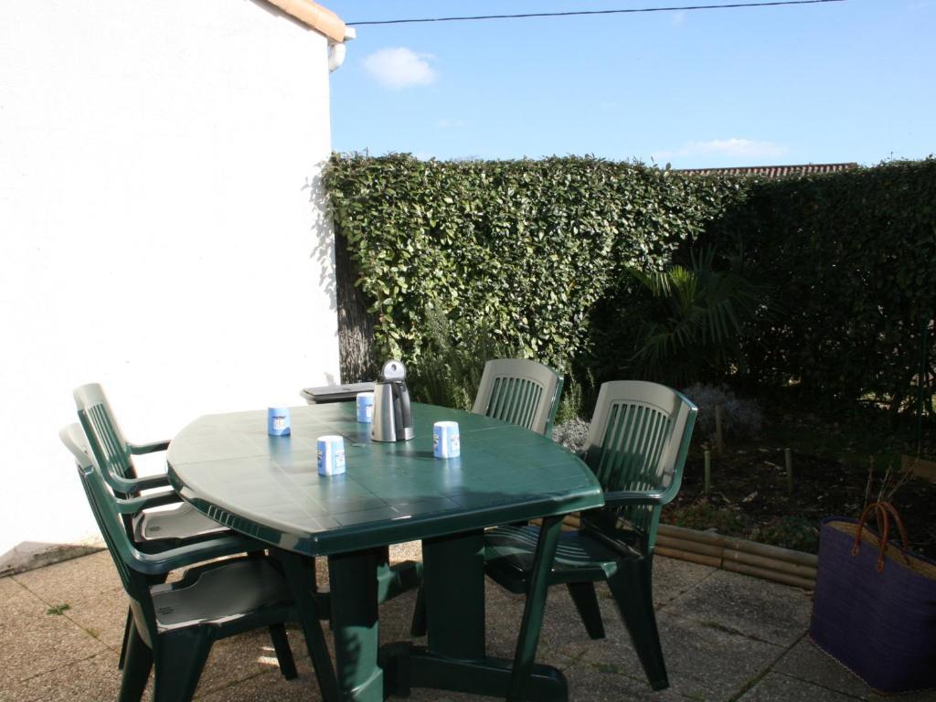 une table et des chaises vertes sur la terrasse dans l'établissement Maison proche plage avec jardin et parking à La Tranche sur Mer - FR-1-22-164, à La Tranche-sur-Mer