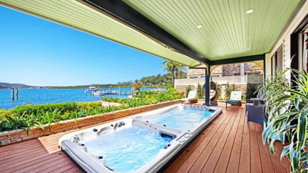 an outdoor hot tub on a deck next to the water at North View - St Huberts in Daleys Point