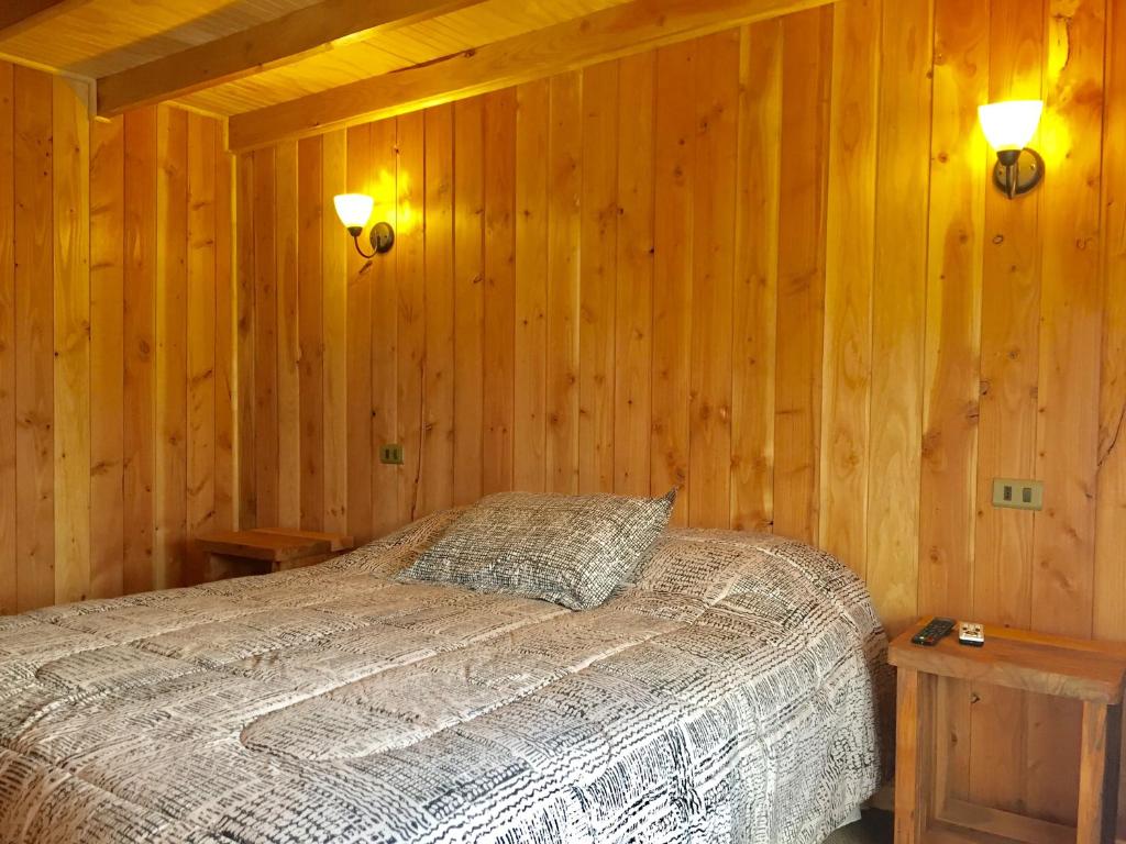 a bedroom with a bed in a wooden wall at Cabañas Choshuenco in Choshuenco