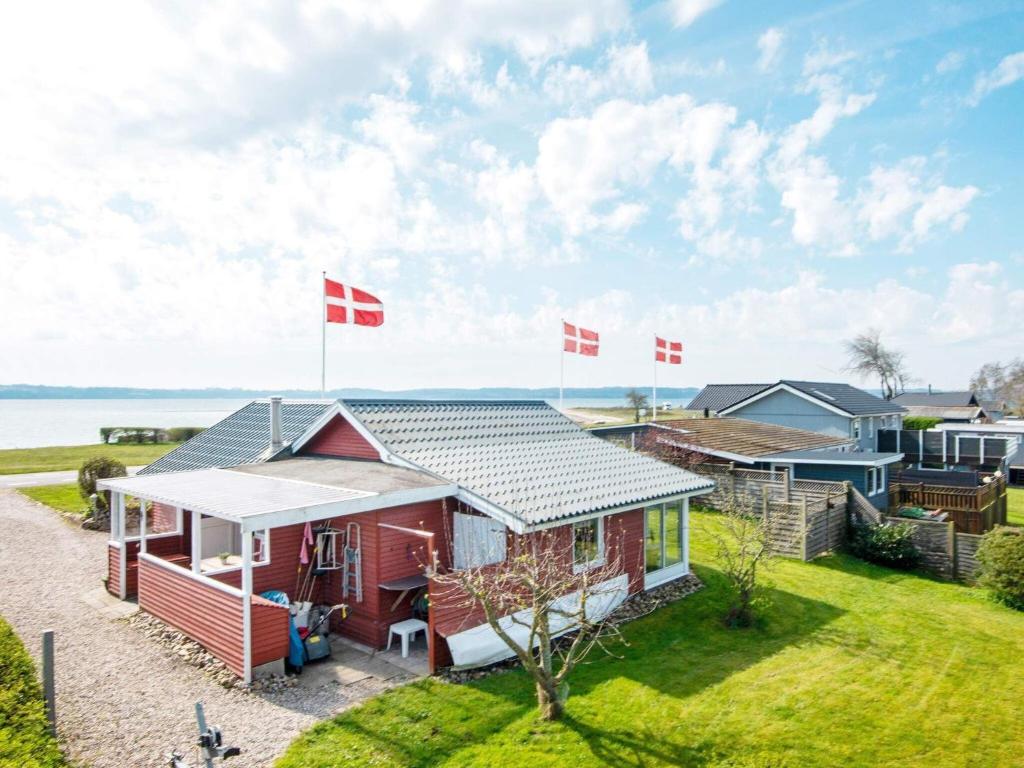 uma casa vermelha com bandeiras em frente à água em Holiday home Aabenraa LXX em Aabenraa