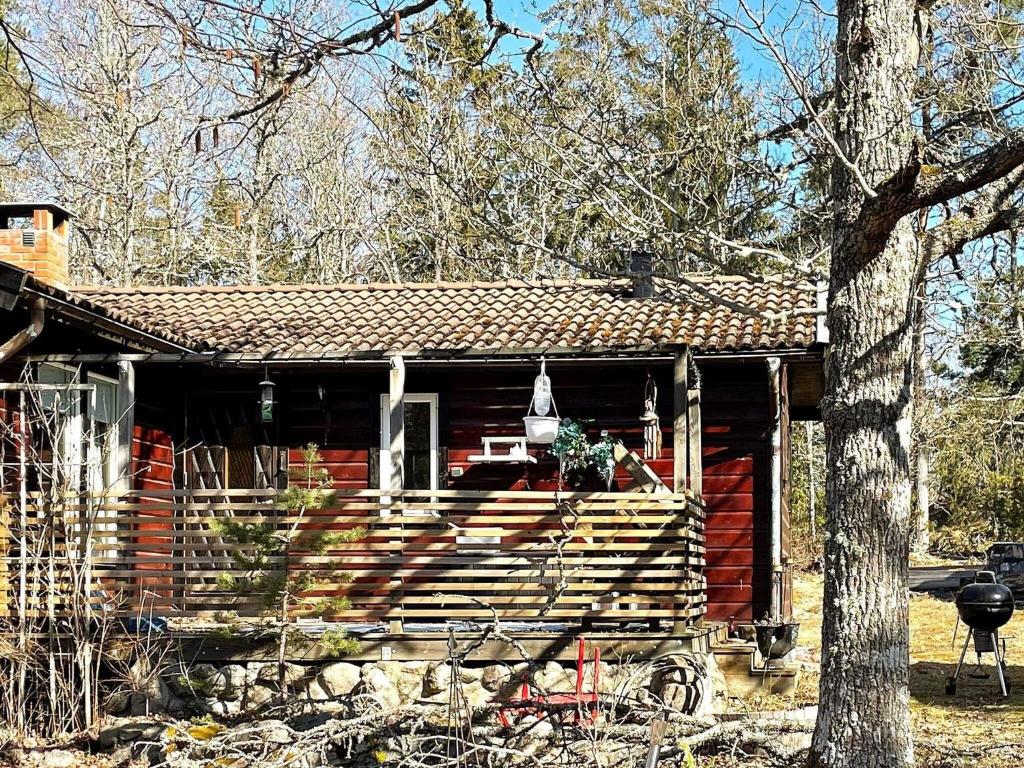Una cabaña roja con un árbol delante. en Holiday home GUSUM II, en Gusum