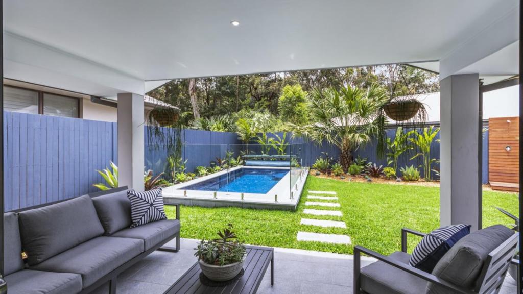 a patio with a couch and a swimming pool at Jewellers Retreat - Pearl Beach in Pearl Beach