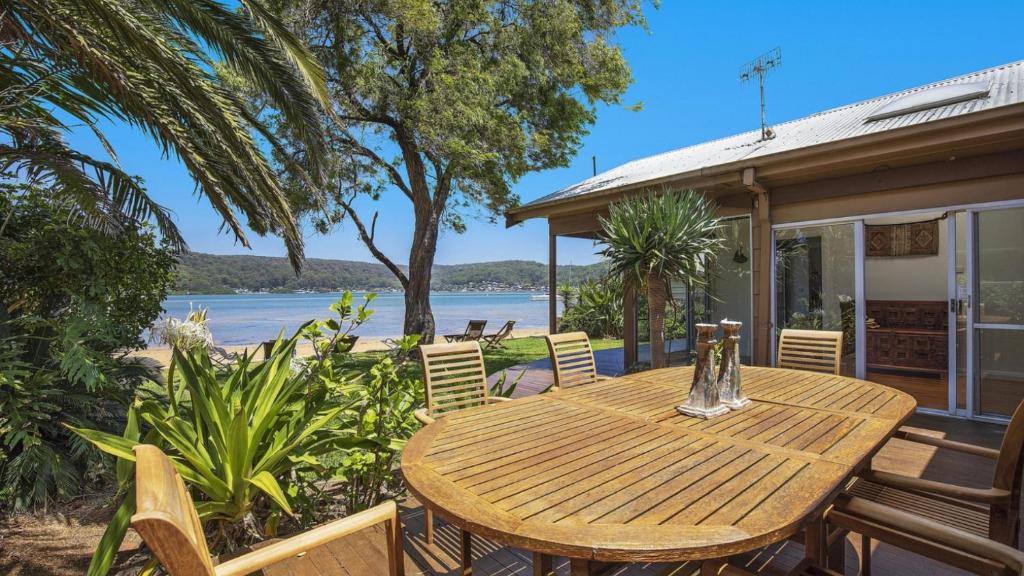 una mesa de madera y sillas en un patio con agua en Booker Bay Beach House Family Fun, en Booker Bay