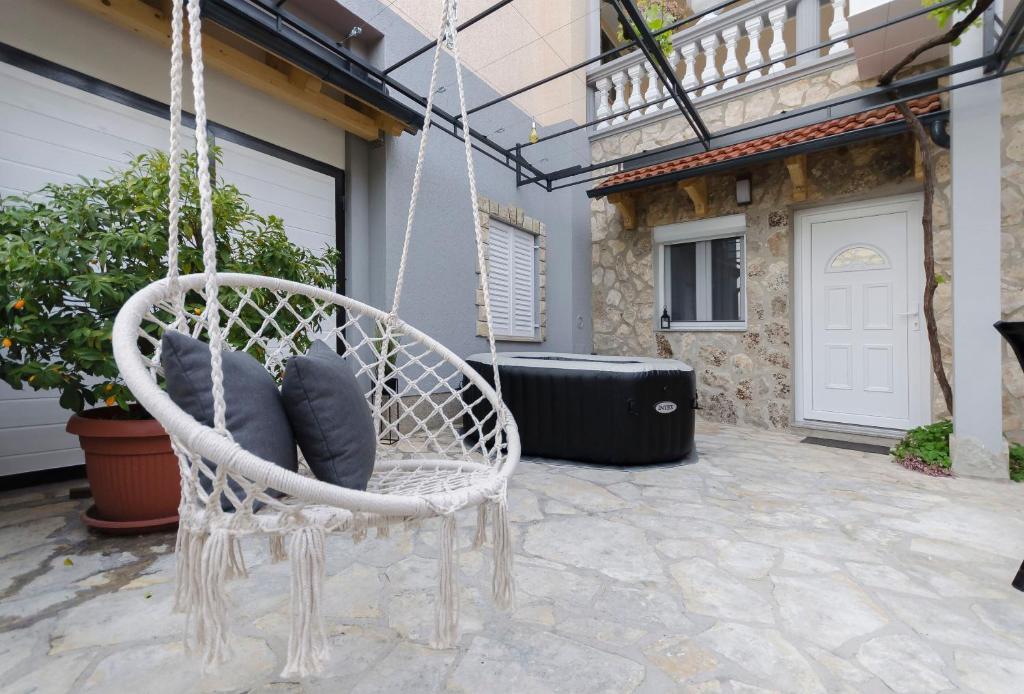 a white swinging chair with pillows on a patio at Apartment Maja with Jacuzzi in Rupe