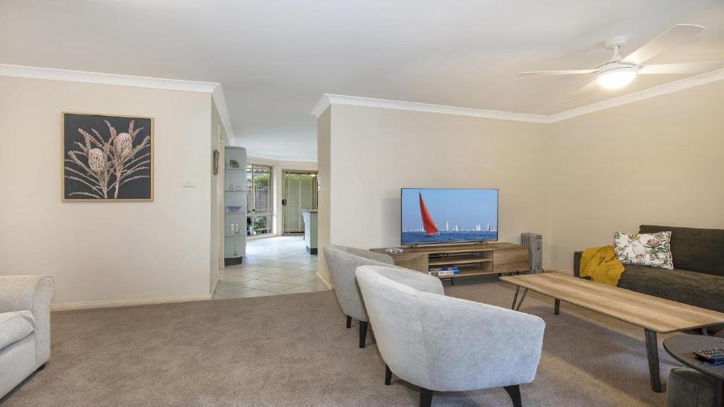 a living room with a couch and a tv at Banksia Villa Umina Beach in Umina
