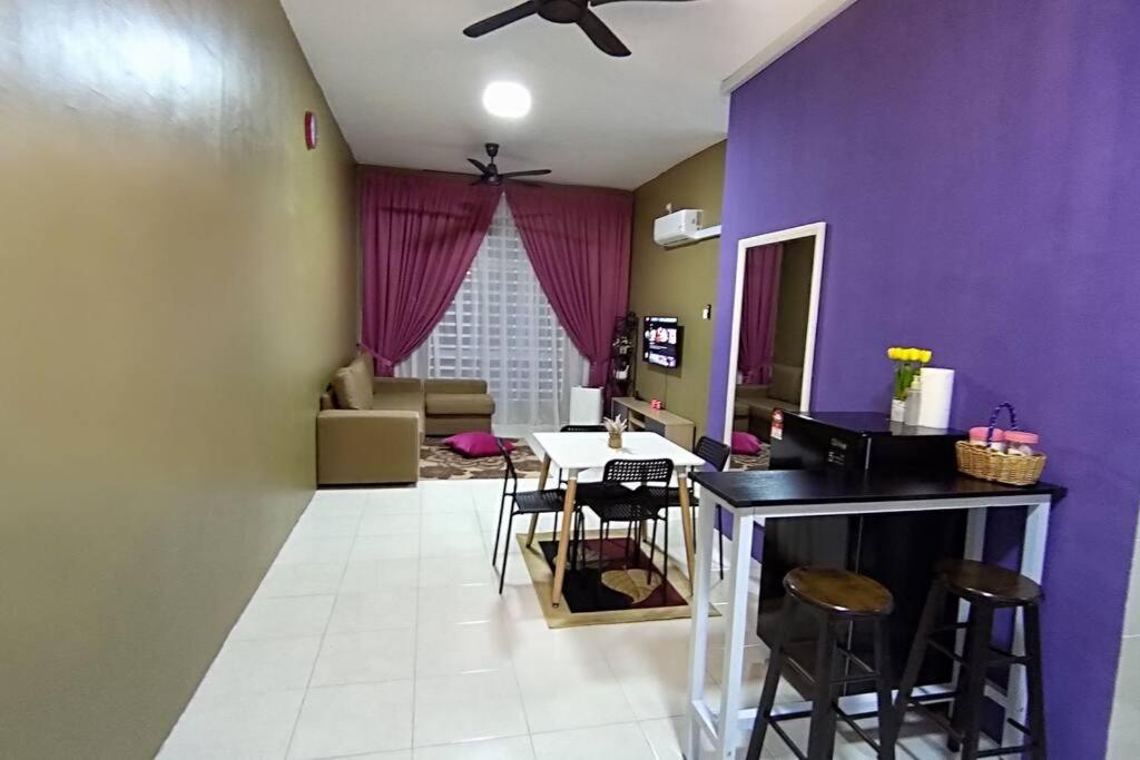een woonkamer met een paarse muur en een tafel en stoelen bij CASA Singgah Homestay in Chemor