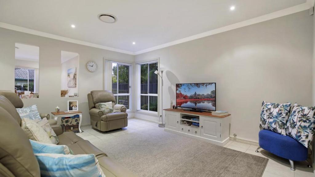 a living room with a couch and a tv at Ocean Beach Holiday House in Ettalong Beach