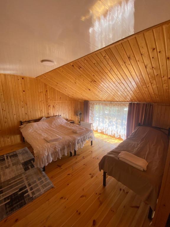 a room with two beds in a wooden room at Sunny Beach Hotel in Cholpon-Ata