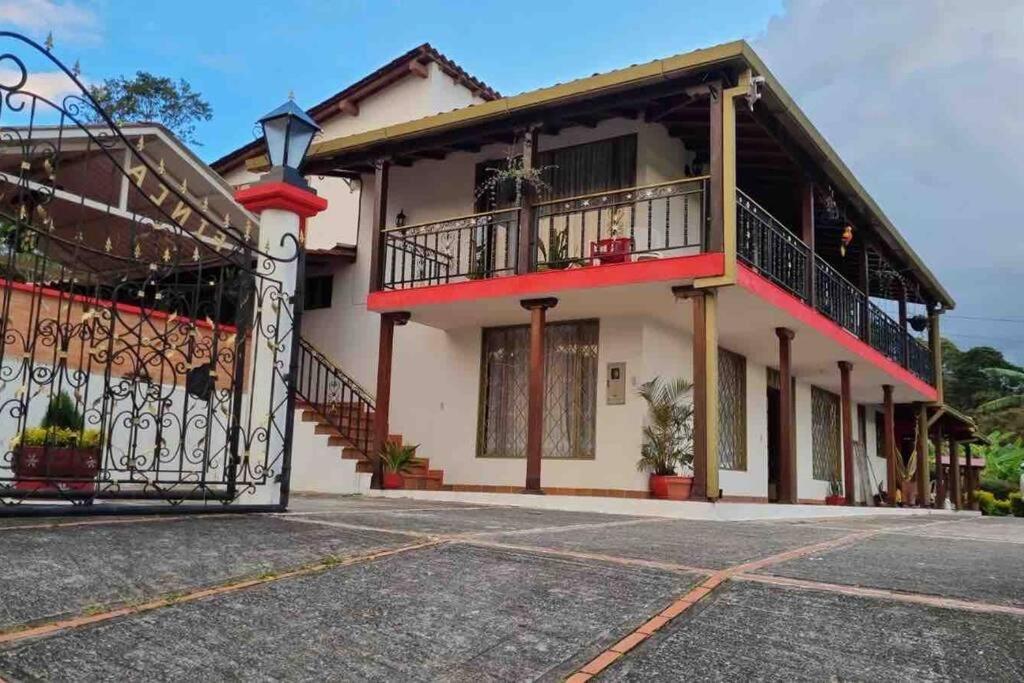 a house with a balcony and a gate at Espectacular casa de campo en finca cafetera in Moniquirá