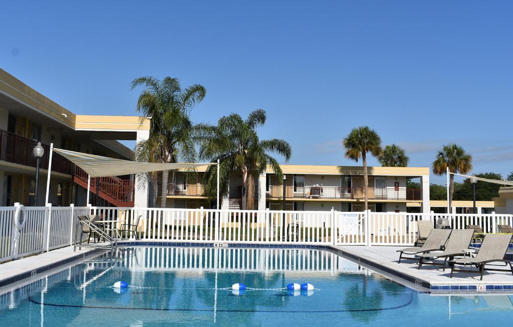 a swimming pool with chairs and a white fence at Super 8 by Wyndham Ocala I-75 in Ocala