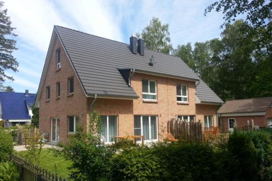 a large brick house with a black roof at Strandvilla Birkenallee Haus Sommerlicht in Neuhaus